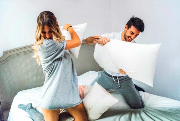 coppia di fidanzati fa una battaglia di cuscini in hotel