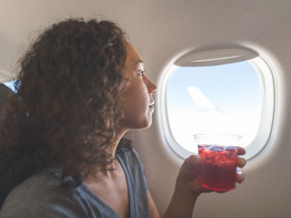 Donna che beve un drink sull'aereo