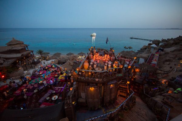 Vista-notturna-del-Farsha-Cafe-illuminato-arroccato-sulla-scogliera-che-domina-il-Mar-Rosso-con-lanterne-luminose-e-accoglienti
